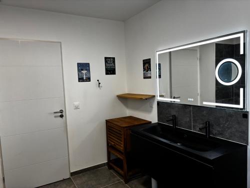 une salle de bain avec un lavabo noir et un miroir dans l'établissement Gîte de Montfort, à Caromb