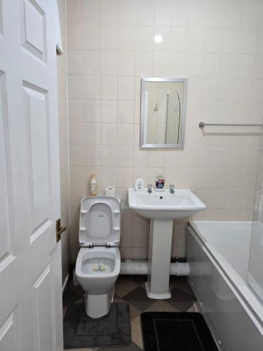 a bathroom with a toilet and a sink and a tub at A City Centre family house in Peterborough