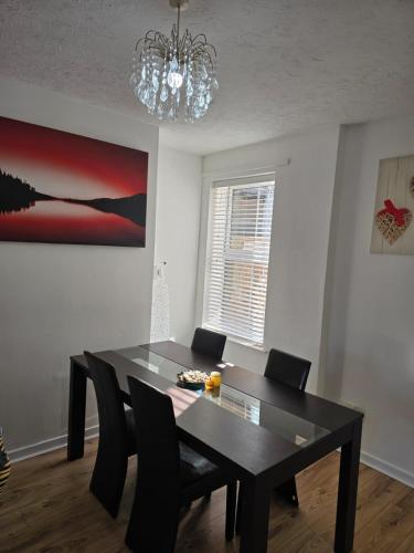 a dining room table with black chairs and a chandelier at A City Centre family house in Peterborough