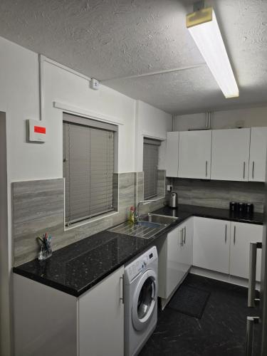 a kitchen with a washing machine and a sink at A City Centre family house in Peterborough
