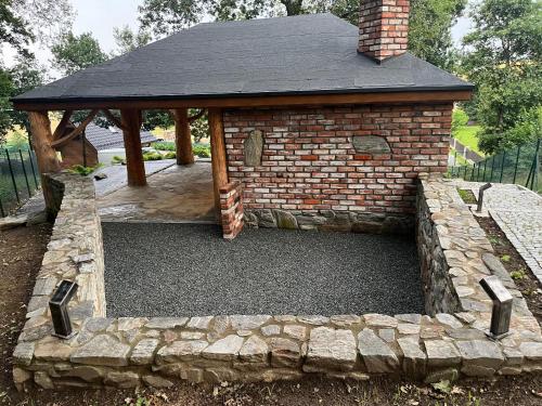 a gazebo in a yard with a stone wall at Domek w Górach Bardzkich in Kamieniec Ząbkowicki