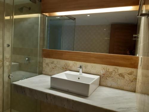 Un baño con un lavabo blanco y un espejo. en SM Comfort Stay, en Dhaka