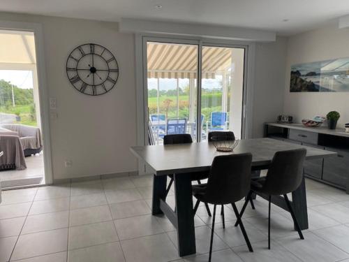 une salle à manger avec une table, des chaises et une horloge dans l'établissement Domaine d'Annégré, à Brem-sur-Mer