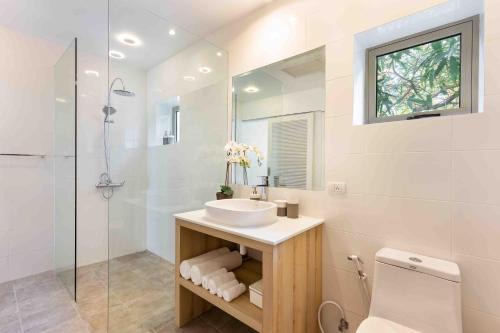 a white bathroom with a sink and a shower at Villa Sand in Pilai Beach