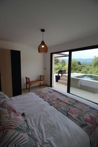 une chambre avec un lit et une grande fenêtre en verre dans l'établissement Les Terrasses de Ruppione - Villa Scandola, à Pietrosella