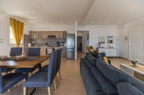 a living room and kitchen with a table and blue chairs at Villa Stavros in Archangelos