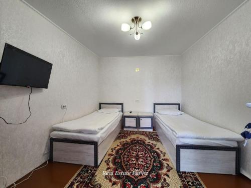 two beds in a room with a flat screen tv at Markhaba in Samarkand