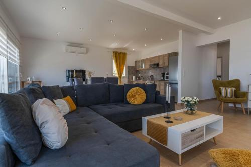 a living room with a blue couch and a kitchen at Villa Stavros in Archangelos