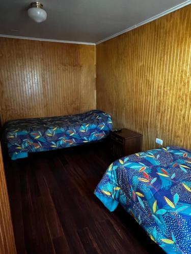 AngolにあるHostal Ginaのウッドフロアの客室で、ベッド2台が備わります。