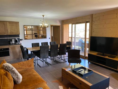 un salon avec un canapé et une table avec des chaises dans l'établissement Champagny Les Alpages, à Champagny-en-Vanoise