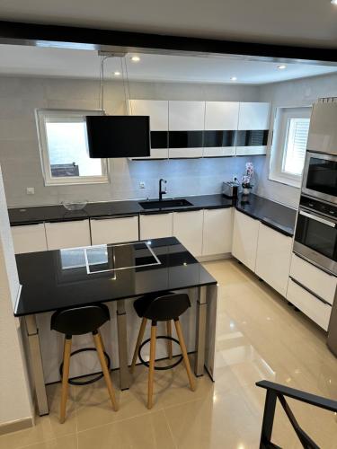 une cuisine avec un comptoir noir et deux tabourets de bar dans l'établissement Villa la Nautilia, au Cap d'Agde