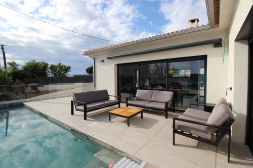 un patio avec deux chaises et une table à côté d'une piscine dans l'établissement Les Terrasses de Ruppione - Villa Restonica, à Pietrosella