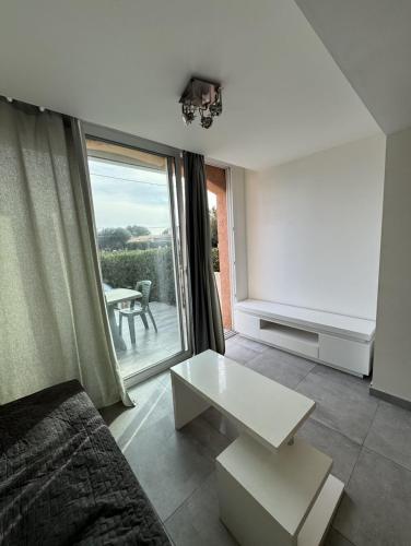 un salon avec un canapé, une table et une fenêtre dans l'établissement Petit Nid Pieds dans l'eau, à Sausset-les-Pins