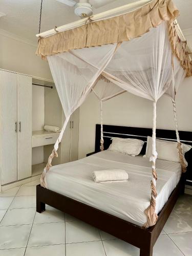 a bedroom with a bed with a canopy at Azar Stays Diani in Diani Beach