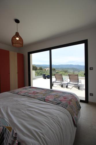une chambre avec un lit et une grande fenêtre dans l'établissement Les Terrasses de Ruppione - Villa Restonica, à Pietrosella