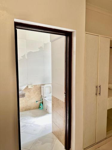 a bathroom with a toilet and a glass door at Azar Stays Diani in Diani Beach