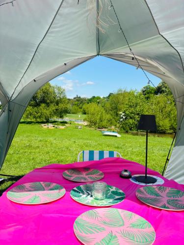 a table in a tent with plates of food on it at Hertford belltent farm stay riverside firepit bbq in Hertford