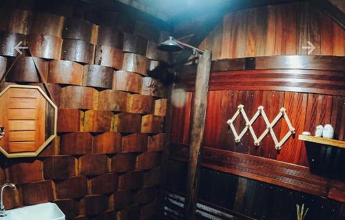 a bathroom with a wooden wall and a sink at Chalé da Árvore Cotijuba COP 30 in Belém