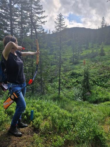 a woman with a bow and arrow in the woods at Haus Andrea in Planneralm