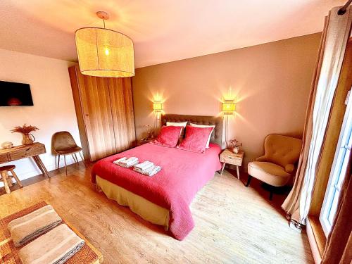a bedroom with a large red bed and a chair at Le Mas Justin in Gordes