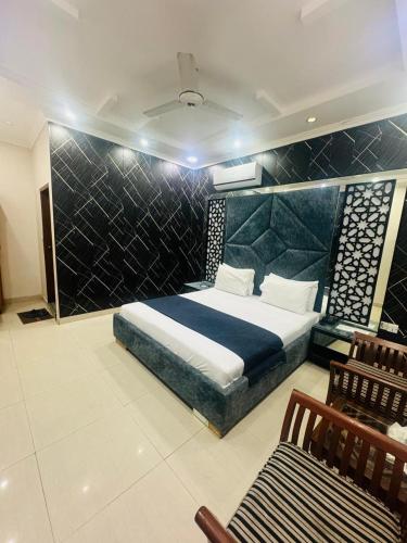 a bedroom with a large bed and two chairs at The Lodge Inn in Karachi