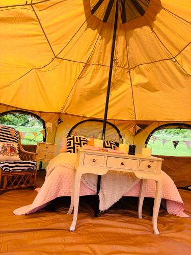 a bedroom with a table in a tent at Hertford belltent farm stay riverside firepit bbq in Hertford