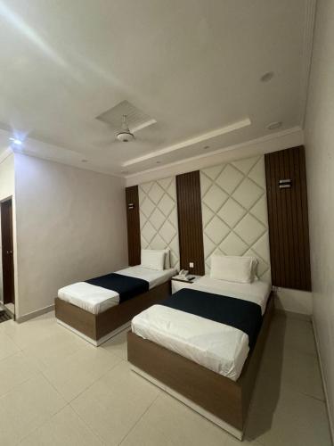 a hotel room with two beds in a room at The Lodge Inn in Karachi