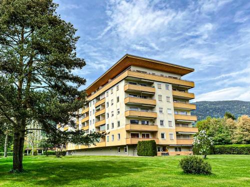 a large apartment building with a tree in a field at RIOpartment Ossiacher See in Bodensdorf