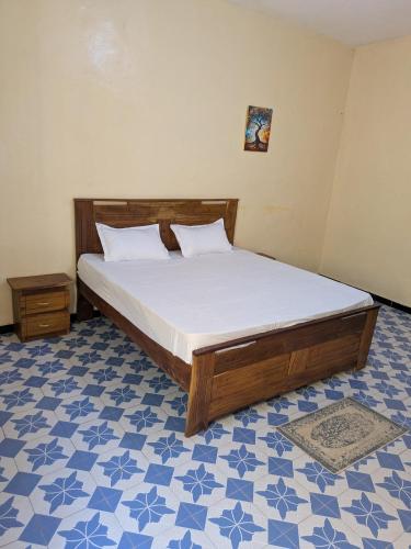 a bedroom with a bed and a blue and white floor at a true haven of peace in Darou Rhamane