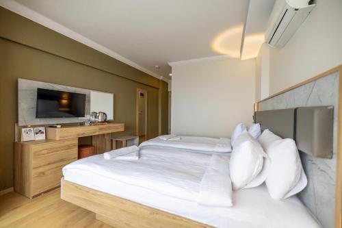 a bedroom with a large white bed and a television at Rest&More by DEDEMAN in Kusadası