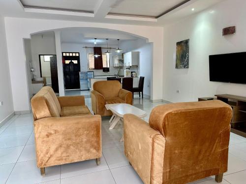 a living room with two chairs and a tv at Clalem Condos Diani Beach in Diani Beach