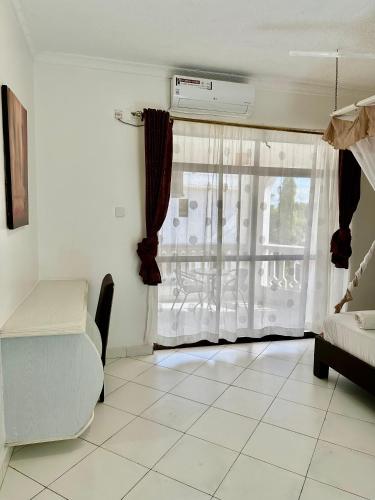 a room with a bed and a window with curtains at Clalem Condos Diani Beach in Diani Beach