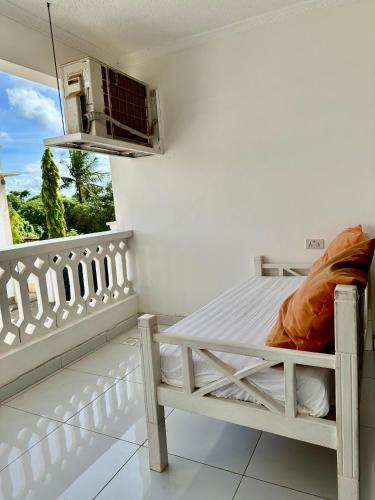 a white bed in a room with a balcony at Clalem Condos Diani Beach in Diani Beach