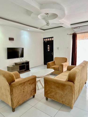a living room with two couches and a tv at Clalem Condos Diani Beach in Diani Beach