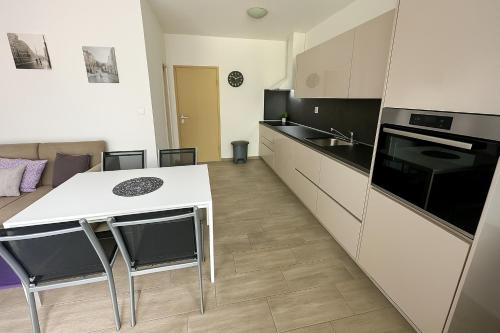 a kitchen with a white table and some chairs at Apartman Citro in Novalja