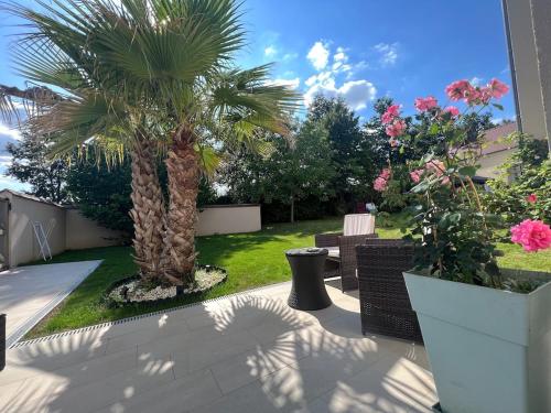 un patio avec deux palmiers, des chaises et des fleurs dans l'établissement Cozy duplex with terrace 3km from Disney, à Magny-le-Hongre