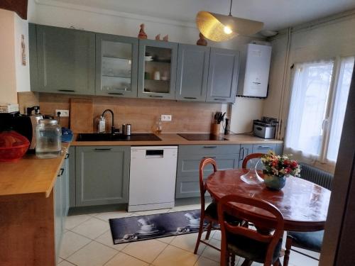 une cuisine avec des placards verts et une table avec des chaises dans l'établissement Maison le Cerisier, à Amiens