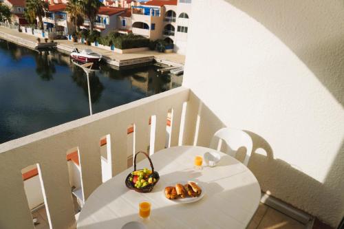 - une table blanche avec un bol de nourriture sur le balcon dans l'établissement Le Nautica Terrasse 2 Pers Piscine, au Barcarès