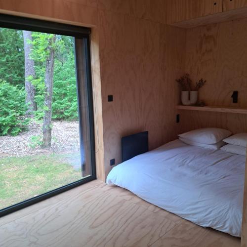 un lit dans une chambre avec une grande fenêtre dans l'établissement Cabin indebos, à Sainte-Foy-de-Longas