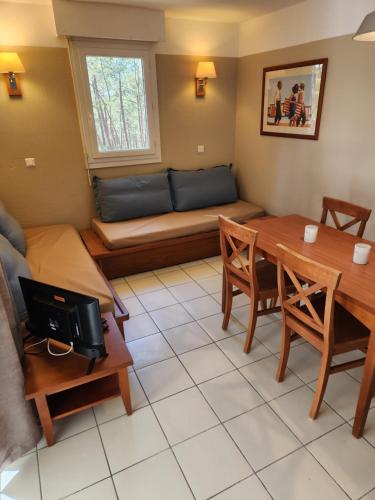 un salon avec une table et un canapé dans l'établissement Résidence les Grands Pins, à Carcans