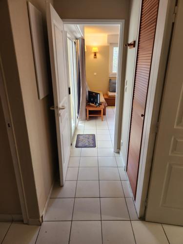 un couloir avec du carrelage et une porte ouverte dans l'établissement Résidence les Grands Pins, à Carcans