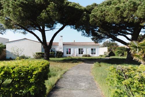 a driveway leading to a white house with a tree at Villa Kenavo - Maison familiale avec vue mer in Île dʼAix