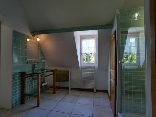 La salle de bains est pourvue de carrelage vert, d'un lavabo et d'une fenêtre. dans l'établissement Les Cyprès du Brel, à Le Mas