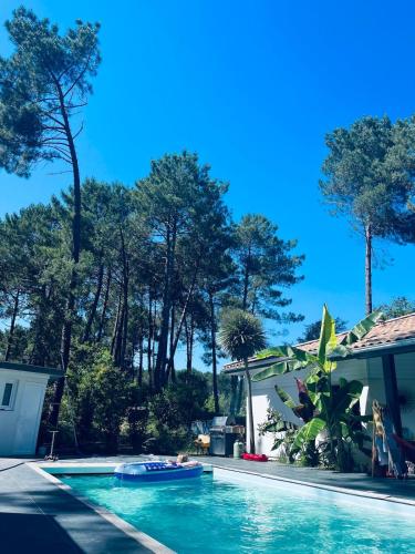 une piscine devant une maison avec des arbres dans l'établissement modern appartement with private garden & shared pool, à Seignosse