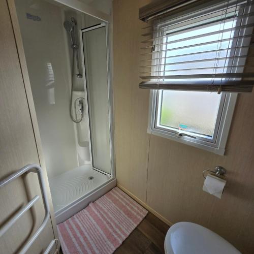 a bathroom with a shower and a toilet and a window at Thornwick bay Yellowhammer 28 in Flamborough