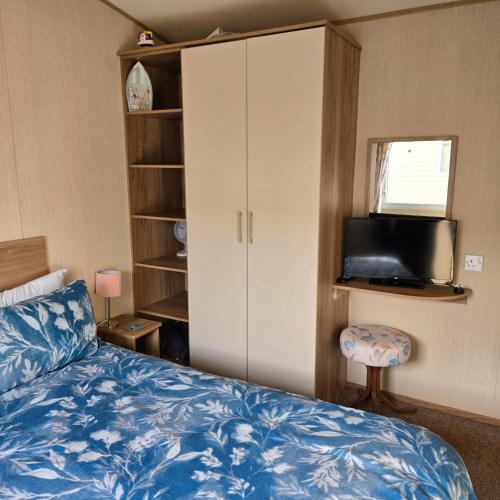 a bedroom with a bed and a cabinet and a television at Thornwick bay Yellowhammer 28 in Flamborough