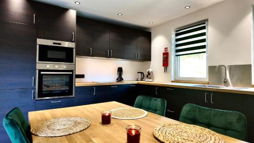 a kitchen with a wooden table with green chairs at Eh ma biche in Stoumont
