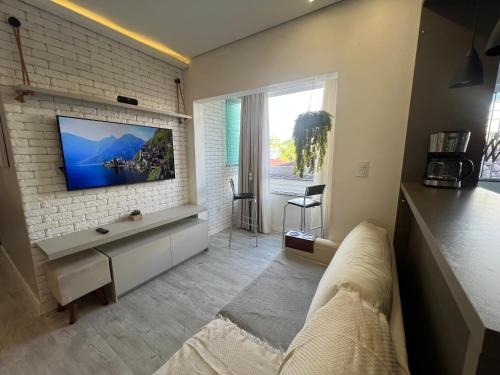 a living room with a tv on a brick wall at Apto moderno - Ao lado Weg - Próx Via verde in Jaraguá do Sul