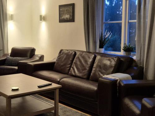 a living room with a brown leather couch and a table at Lodge Short-Long stay in Kramfors