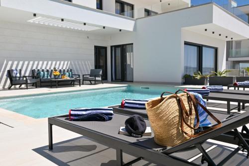 a swimming pool with tables and chairs next to a house at Villa Oasis in Trogir